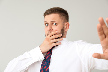 Businessman having panic attack on light background