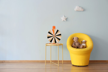 Armchair and table with toys near light wall in children's room