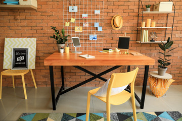 Workplace with mood board near brick wall in modern room