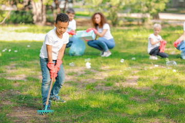 Little African-American volunteer gathering garbage in park