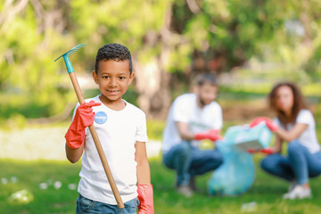 Little African-American volunteer gathering garbage in park