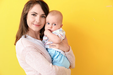 Happy mother and cute little baby on color background