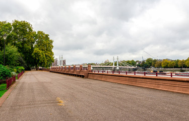 Promenade on the south side of Thames river in Battersea park with a view to Albert Bridge to Chelsea, London, United Kingdom