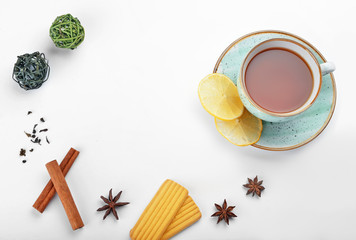 Cup of tasty tea with spices and cookies on white background