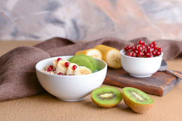 Bowl with tasty oat flakes and fruits on table