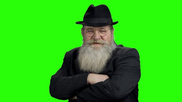 Senior man with crossed man on green screen. Confident elderly man with long beard on Alpha Channel background, front view.