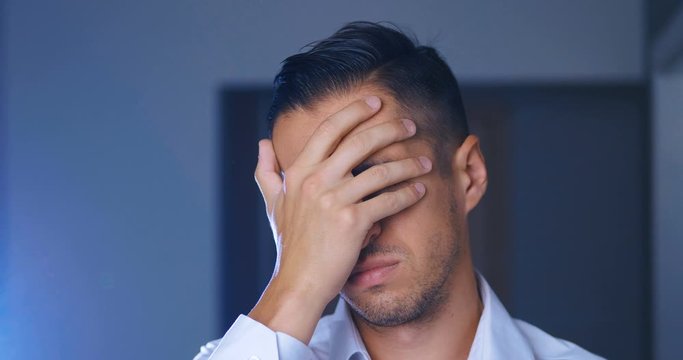 Portrait of Business Man covering face like Facepalm expressing Frustration or Shame. Young Man is Disappointed and covers his face with his hand.