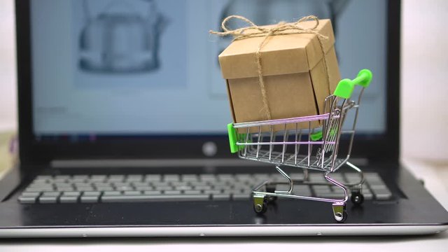 Box in market trolley on a laptop keyboard. against the background of an online grocery store. online shopping for home with delivery