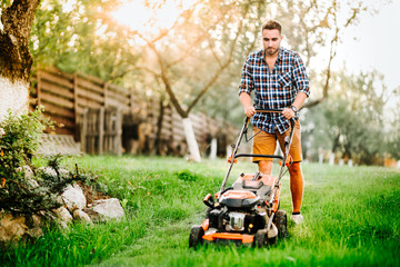 Garden and grass maintainance details - close up view of grass mower and worker . - obrazy, fototapety, plakaty