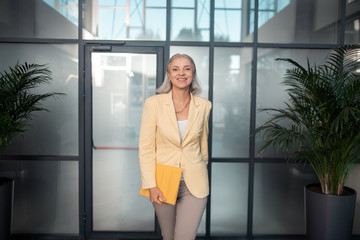 Fototapeta na wymiar Contented senior businesswoman with a yellow paper folder