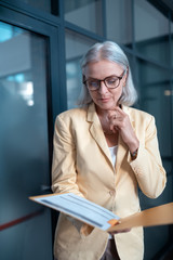 Concentrated stylish businesswoman in a pale yellow jacket