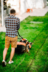 Fototapeta premium Garden maintenance details - portrait of gardener with grass mower.