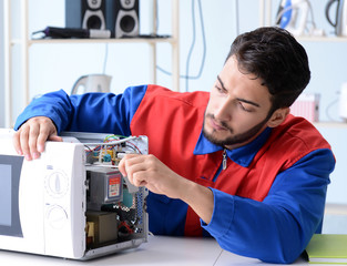 Young repairman fixing and repairing microwave oven