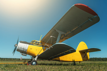 Vintage aircraft on green grass and blue sky background in sunlight. Old retro airplane