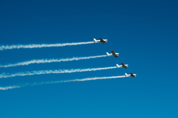 Airplanes with white smoke traces on air show. Pilots make tricks on jets at blue sky background