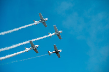 Airplanes with white smoke traces on air show. Pilots make tricks on jets at blue sky background