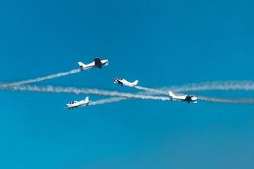 Airplanes with white smoke traces on air show. Pilots make tricks on jets at blue sky background
