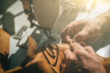 Working process of leather craftsman. Tanner or skinner sews leather on a special sewing machine, close up