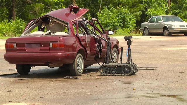 Police and army troops use a remote control robot to diffuse a bomb in a car.