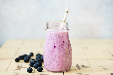 Blended blueberry smoothie in glass with a drinking straw. Healthy refreshing vitamin drink