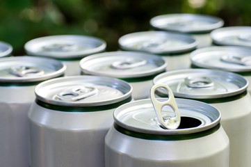 Open close-up of an aluminum can of beer on the background of a group of closed beer cans