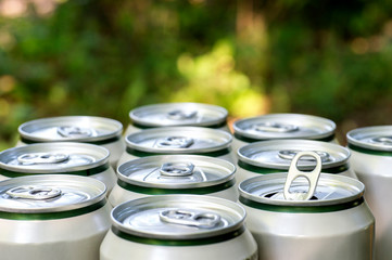 Open close-up of an aluminum can of beer on the background of a group of closed beer cans on a...