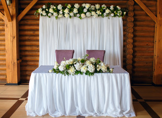 Wedding decor of the restaurant, the table of the newlyweds on a wood background, beautifully decorated decor