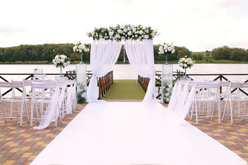 Wedding. Ceremony. Wedding arch. Wedding arch made of branches, flowers and greenery is on the...