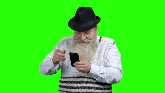 Retired man with beard using mobile phone. Funny old man with smartphone playing game on Alpha Channel background. Senior people, modern technology and fun.