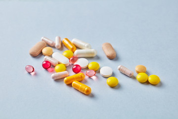 Multicolor vitamins and supplements on bright paper background. Concept for a healthy dietary supplementation. Copy space. 