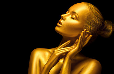 Model girl with shiny golden professional makeup over black. Beauty sexy woman with golden skin. Fashion art portrait closeup. Gold jewellery