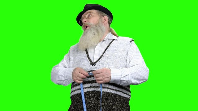 Upset man with a tape measure on green screen. Frustrated old man measures his belly with a measuring tape. Weight loss probelm. New start for healthy lifestyle.