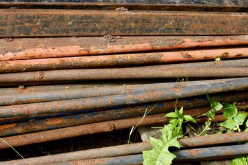 Old, rusty, dirty pipes are piled horizontally. Metal texture for background. Selective focus. 