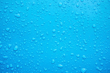 Close up of raindrops, water drops on a polished blue metal surface for background purpose. Selective focus