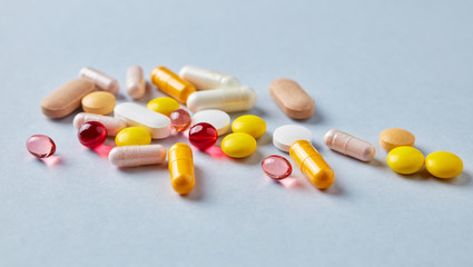 Multicolor vitamins and supplements on bright paper background. Concept for a healthy dietary supplementation. Copy space. 