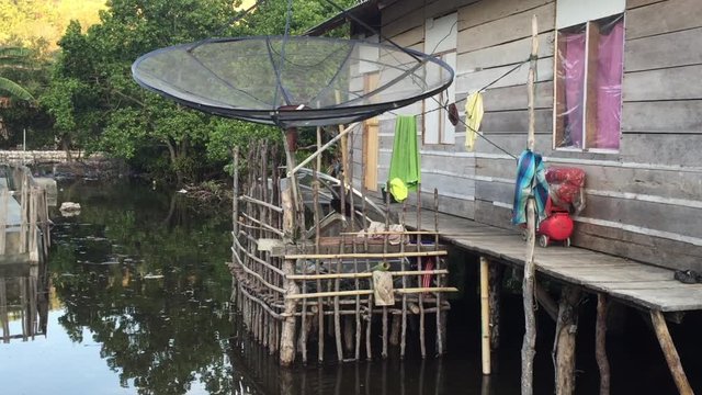 Satellite Dish attached to village shack in Indonesia above water.