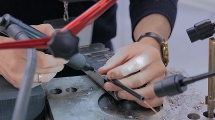 Professional male welder trying to work with gas tungsten arc welding (GTAW) or tungsten inert gas (TIG) technology at exhibition or trade show - close up view. Industrial and engineering work concept