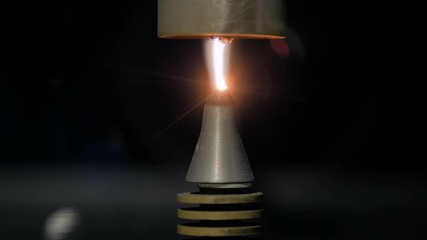 Interactive exposition in science museum, exhibition - portable plasma beam lighter machine with warm light lens flare in dark room - close up view. Electric, physics, experiment, technology concept