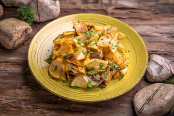 Homemade fried potatoes with mushrooms, paprika and greens.