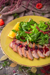 Sliced duck fillet in berry sauce with green salad with pine nuts