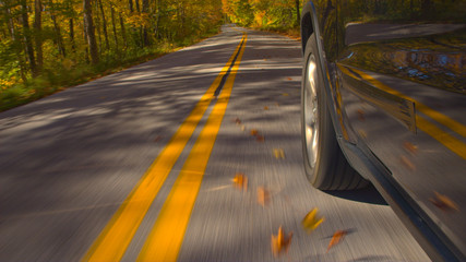 CLOSE UP: Detail of SUV car tire driving on empty forest road in sunny autumn