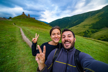 happy tourist backpackers couple taking selfie photo in Stepantsminda also called Kazbegi, Georgia...