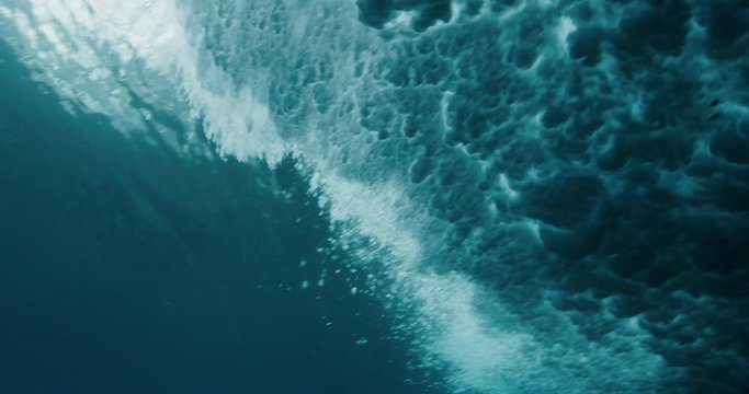 Underwater shot of blue wave crashing on the ocean's surface