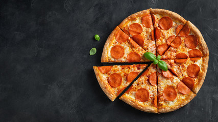 Tasty pepperoni pizza and cooking ingredients tomatoes basil on black concrete background. Top view...