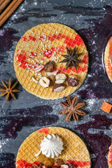 Sweet dessert on dark background. Traditional breakfast with gaufre, waffle, crispy wafer with nuts, fruits and syrup.