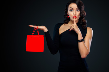 Fototapeta na wymiar Black friday sale concept. Shopping woman holding red bag isolated on dark background