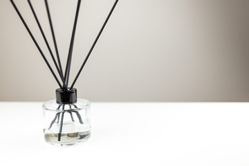 Aromatizer or perfume stick. Aromatic air freshener in a transparent glass bottle with black reeds on a white table