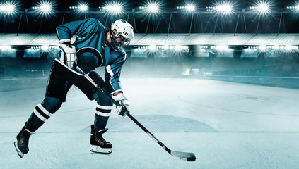 Ice Hockey player athlete in the helmet and gloves on stadium with stick. Action shot. Sport...