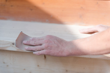 Sand the wood with sandpaper. A man polishes a tree. Work with sandpaper. To make wooden products. Make boards smooth.