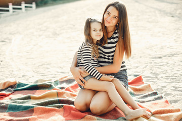 Family sitting on the sand. Mother in a t-shirt. Cute little girl